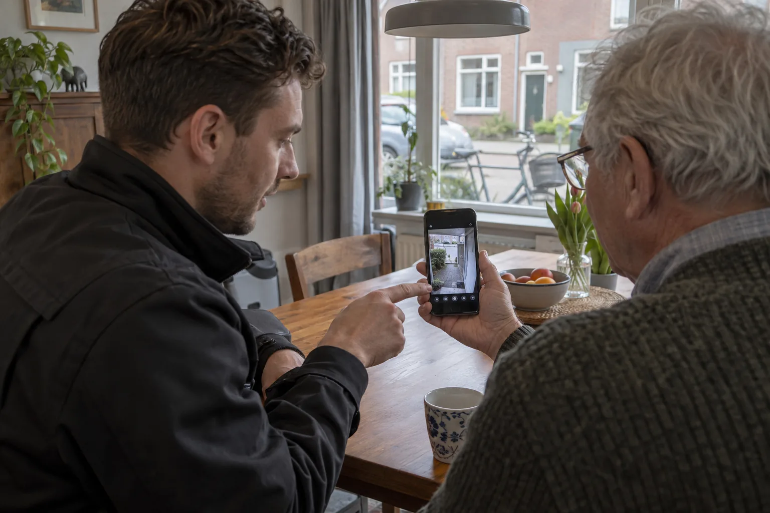 Monteur geeft thuis uitleg over live camerabeeld op een telefoon